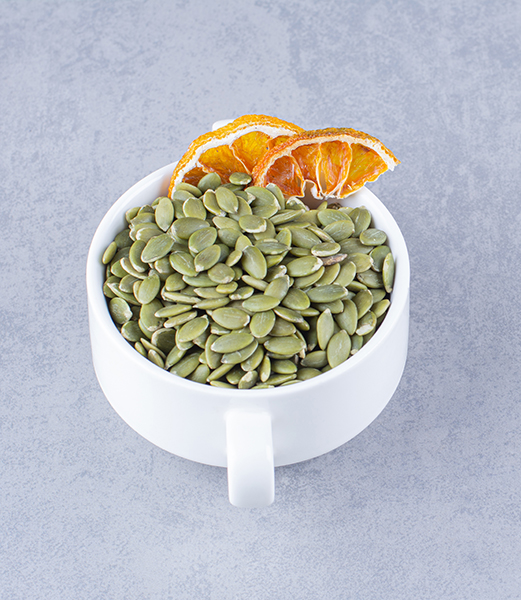 A cup of tasty pumpkin seeds with dried lemon, on the marble background