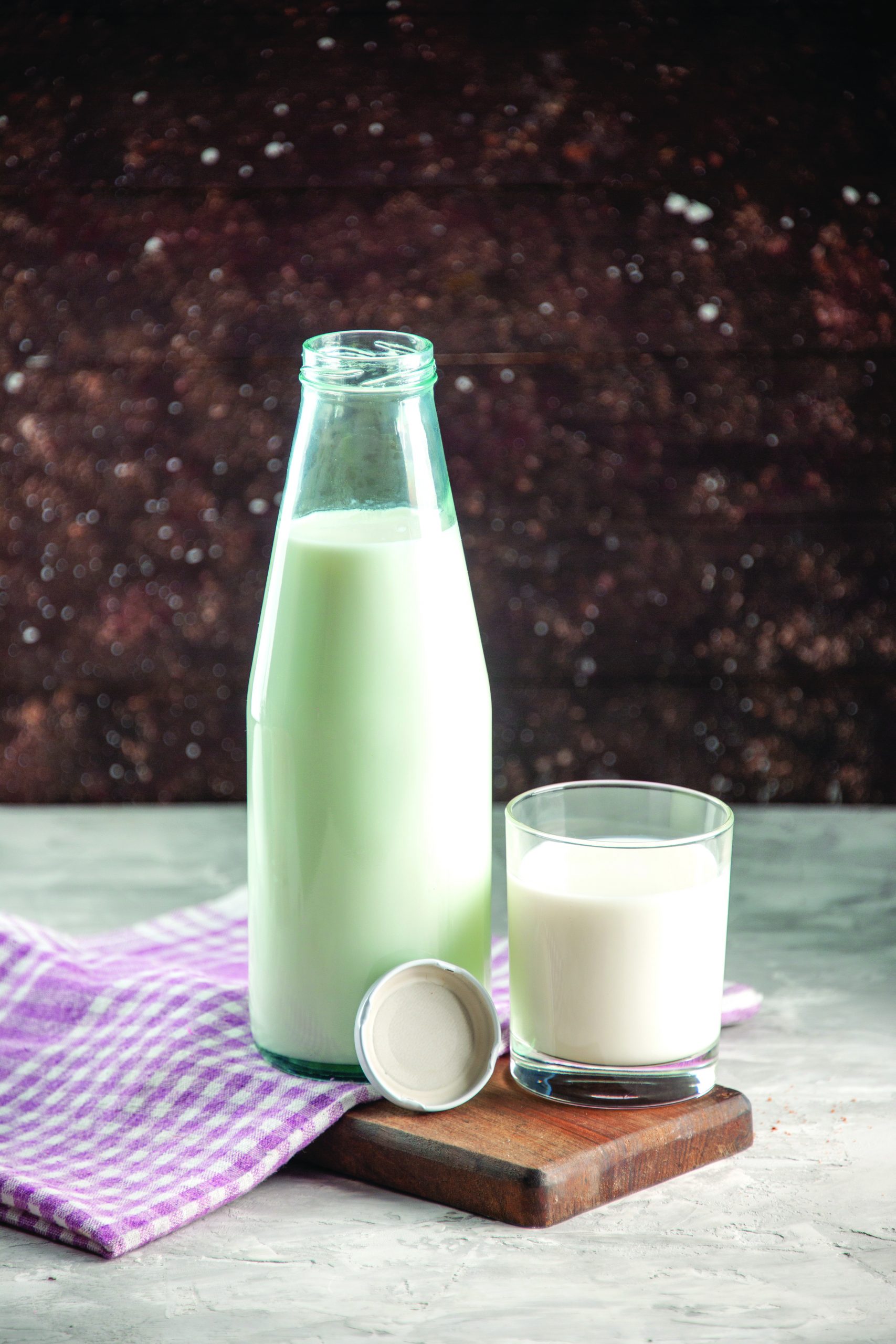 Vertical view of open glass bottle and cup filled with milk on p