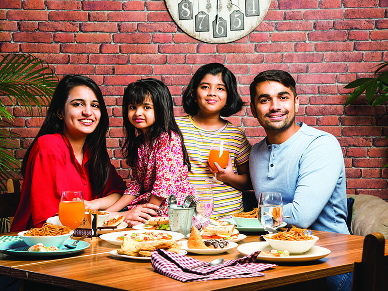 Indian,Young,Family,Of,Four,Eating,Food,At,Dining,Table