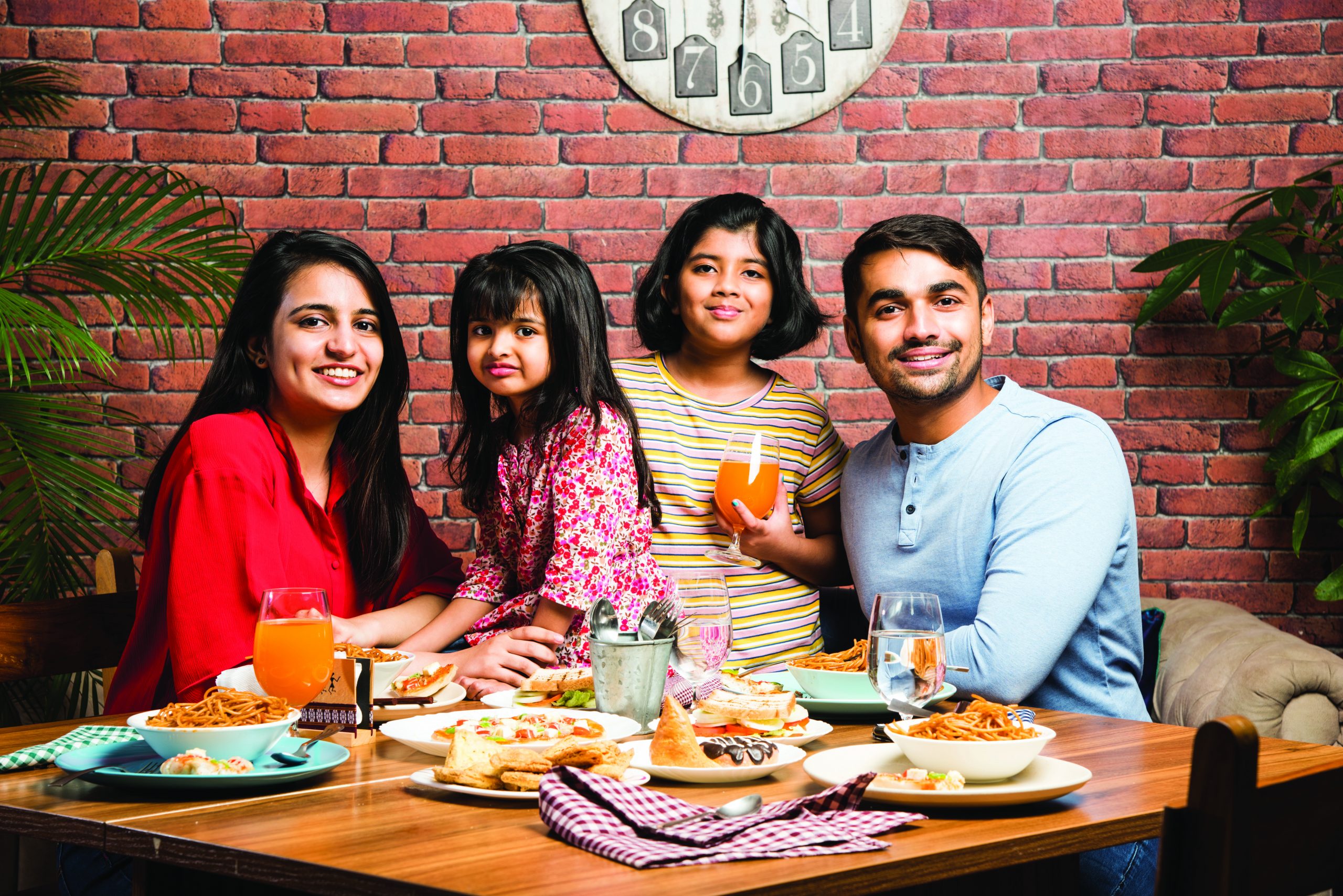 Indian,Young,Family,Of,Four,Eating,Food,At,Dining,Table