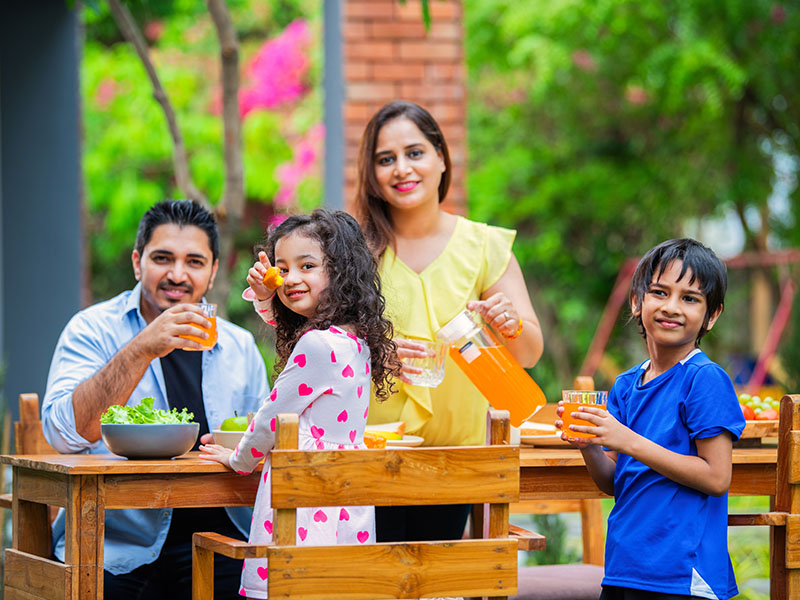 Indian,Young,Family,Of,Four,Eating,Meal,On,Dining,Table