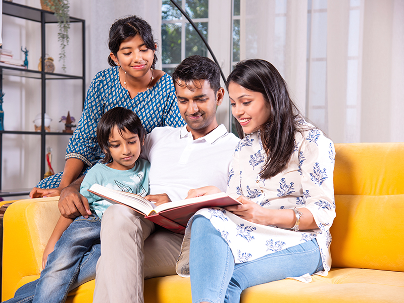 Indian,Asian,Young,Family,Of,Four,Looking,At,Photos,In