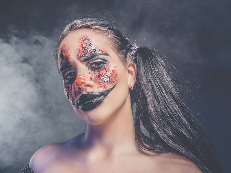 Portrait of evil creepy clown at dark photo studio
