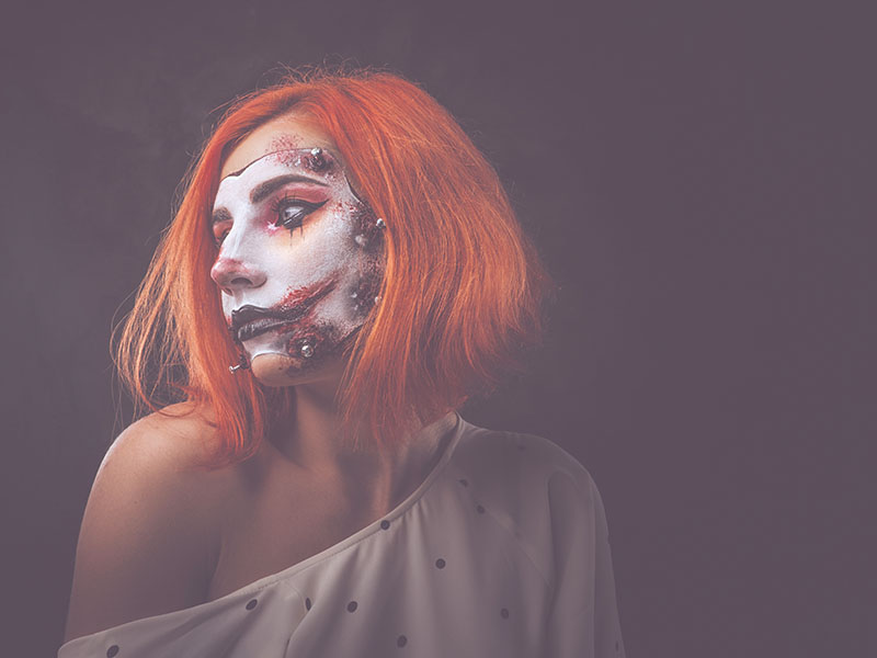 Portrait of ginger girl with scary doll art on face
