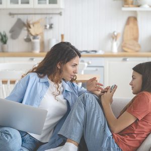 Confused,Teenage,Girl,Looking,At,Mother,Scolding,For,Using,Mobile
